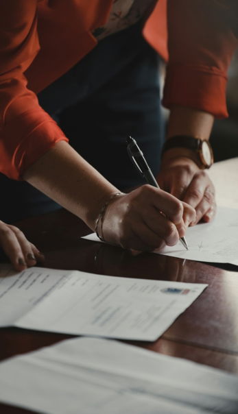 person in orange long sleeve shirt writing on white paper